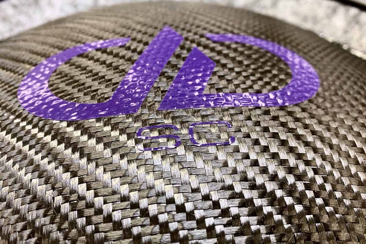 Close up of USA Made subwoofer with purple DDA logo on black carbon fiber dust cap with purple super charged decal