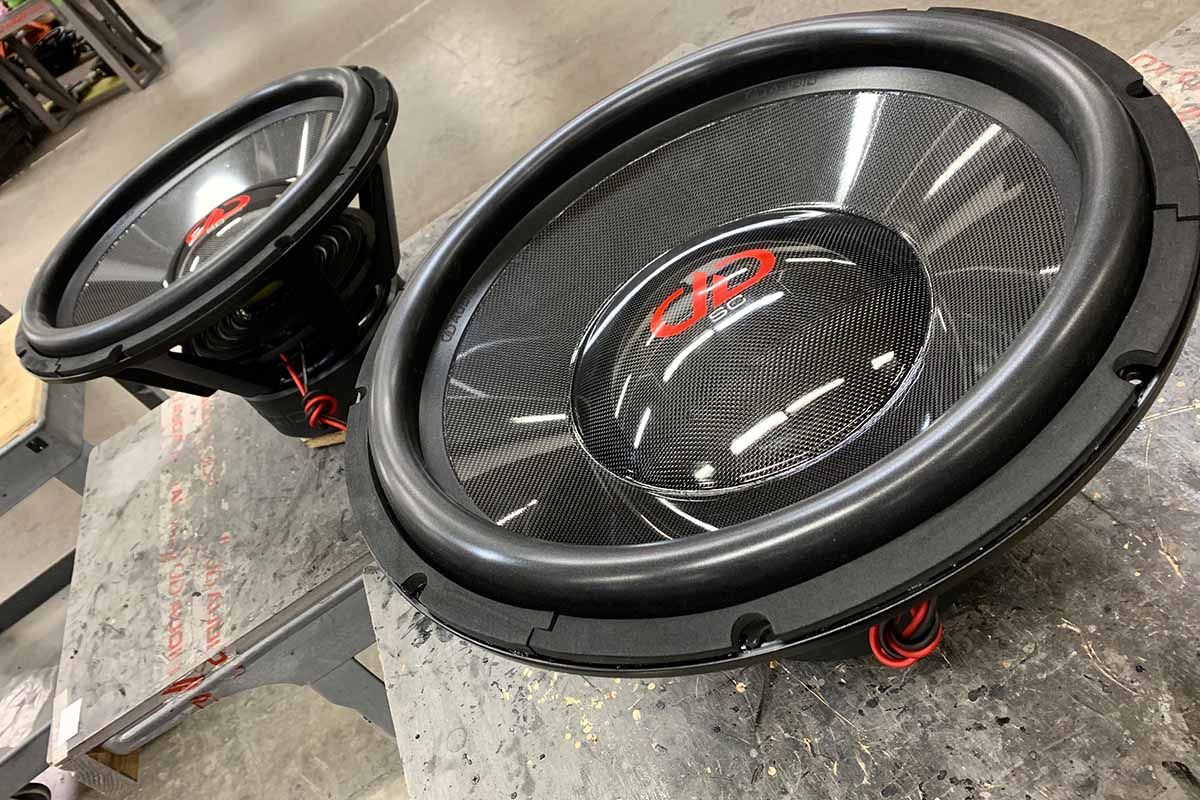 Two USA Made Subwoofers with high gloss carbon fiber cones and dust caps with red DDA logos and Super Charge decal