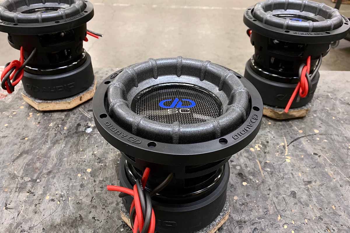 Three USA Made Subwoofers with high gloss carbon fiber dust caps, blue DDA logos and white Super Charged white decals