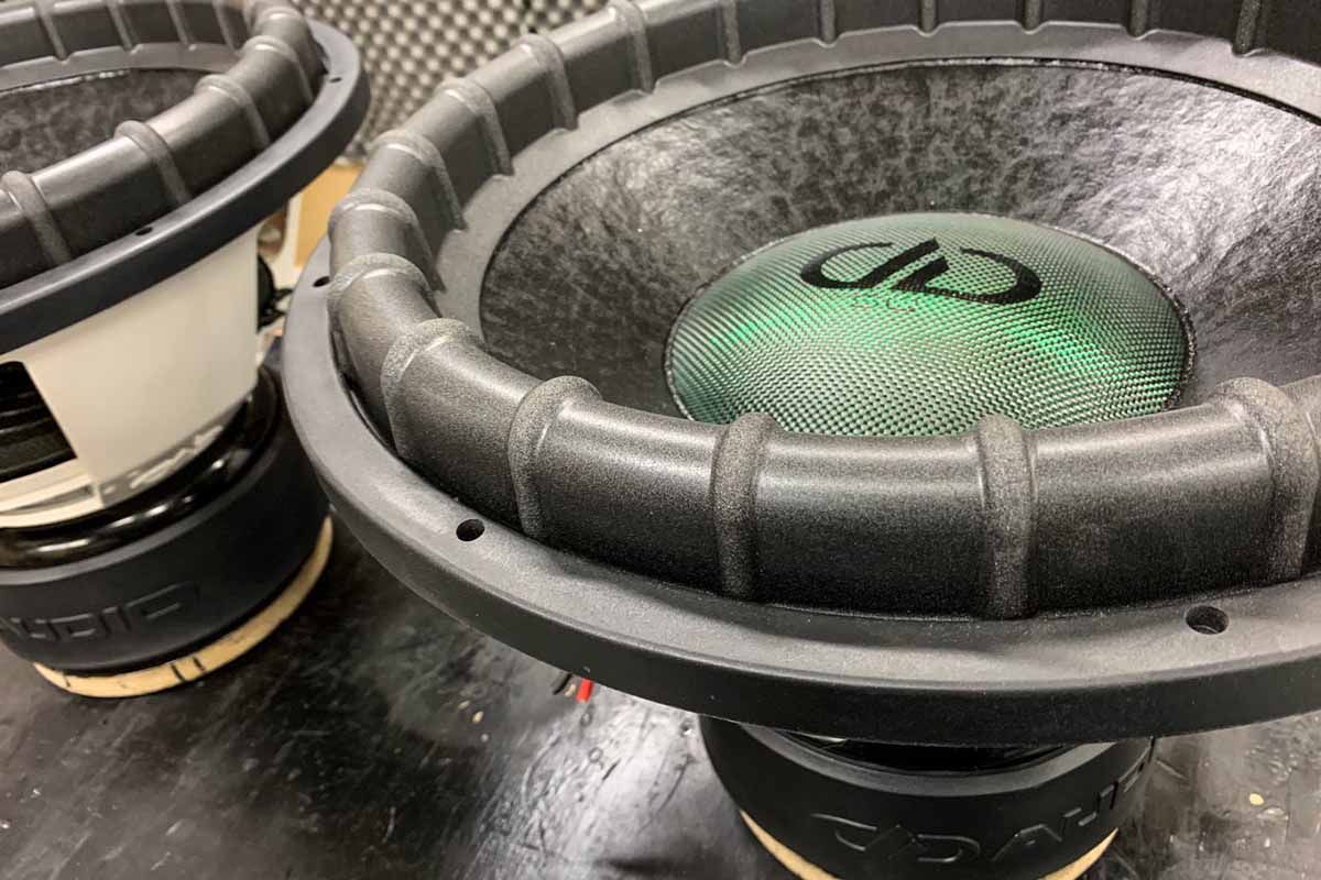 Two USA Made Subwoofers with black cones, metallic green dust caps, black DDA logos, and black Super Charged decals