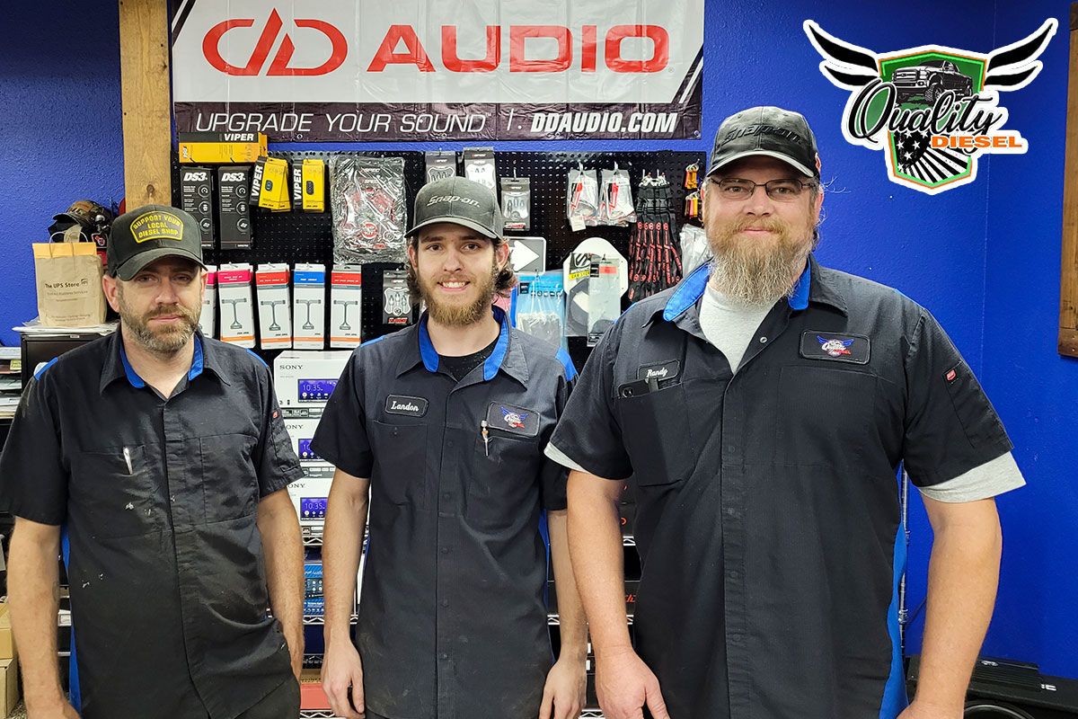 Photo of Quality Diesel staff in lobby under DD banner