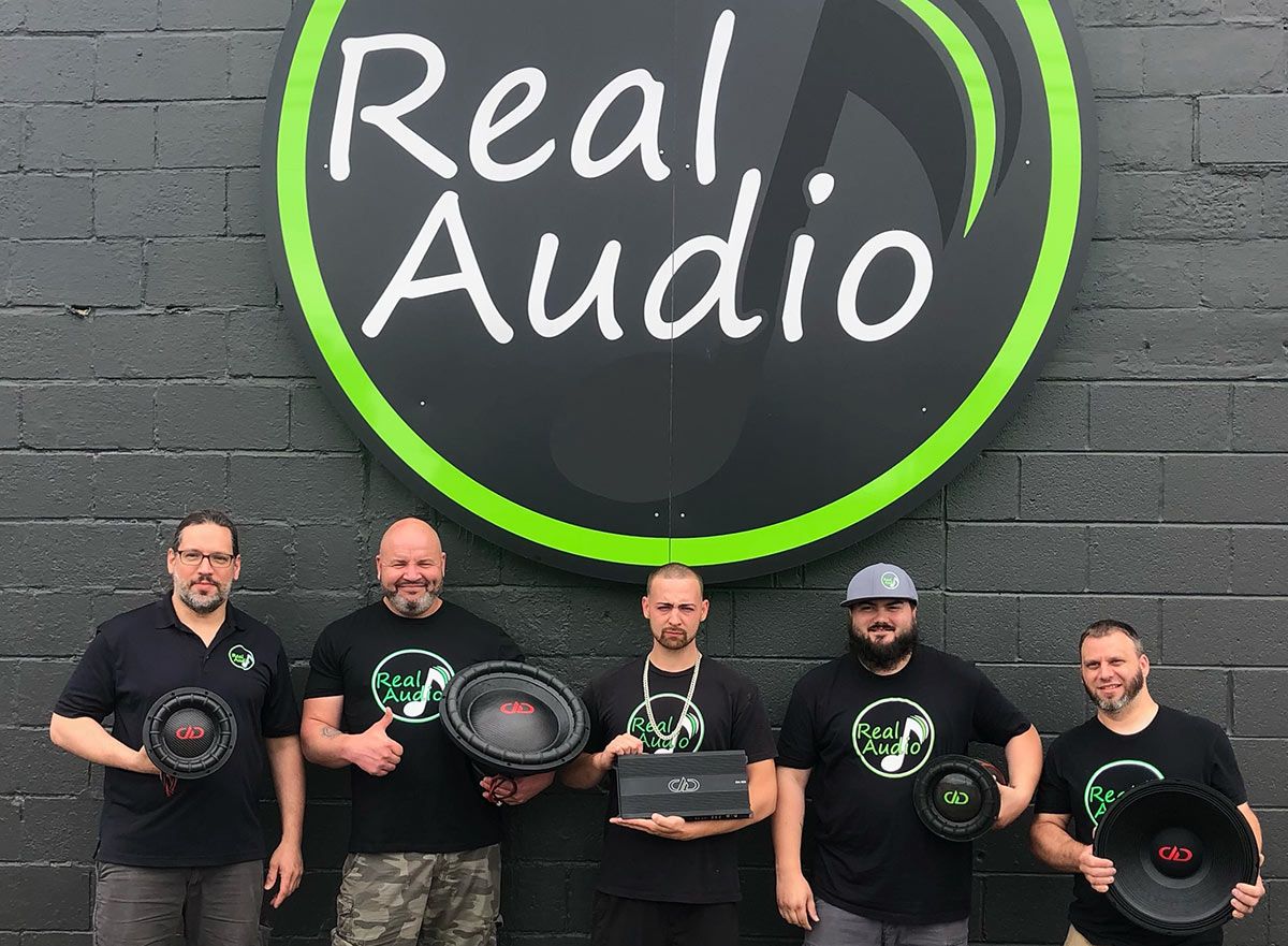 Photo of Real Audio staff in front of their sign at the shop