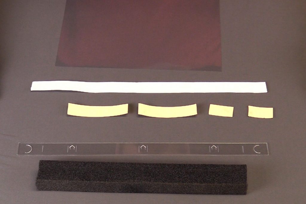 The components needed for a face shield, foam, elastic band, double sided tape, mylar sheet and laser cut  strip